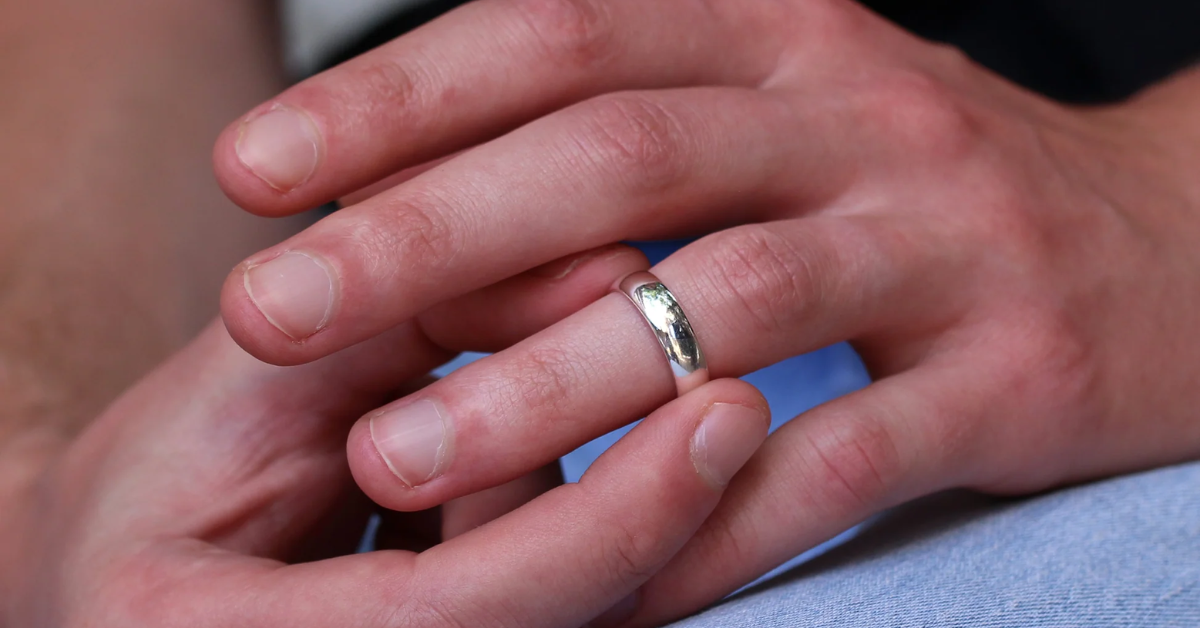 A man holding his silver wedding ring 